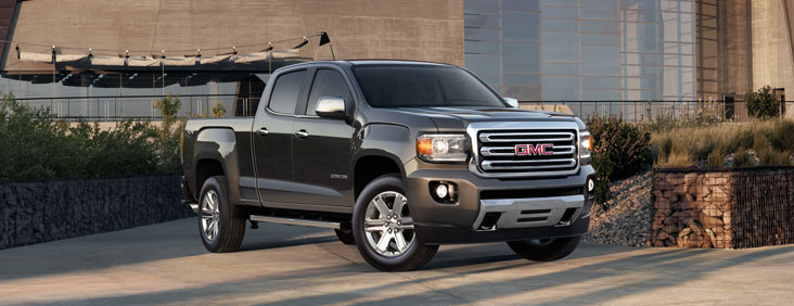 Image of the 2017 GMC Canyon small pickup truck parked in front of a building.