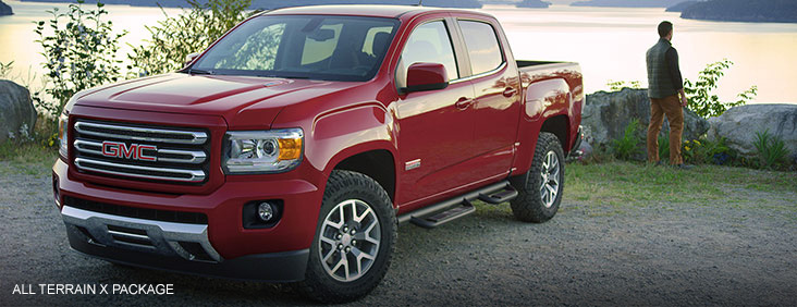 Image of the 2017 GMC Canyon All Terrain X parked in front of a lake near mountains.