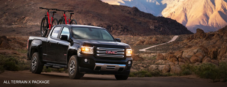 Image of the 2017 GMC Canyon All Terrain X driving on a mountain rode with two bicycles in the bed.