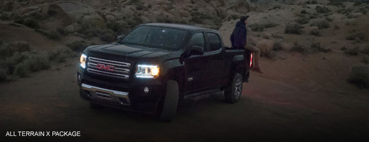 Image of the 2017 GMC Canyon All Terrain X parked below a night sky with a man sitting in the bed.