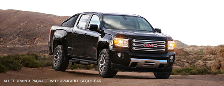 Image of the 2017 GMC Canyon All Terrain X with available sport bar driving on a dirt road.